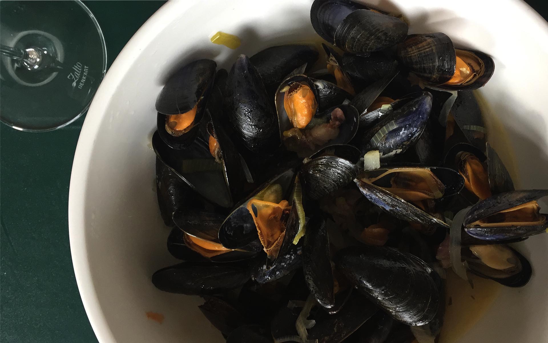 Eine Schüssel Buchot-Muscheln. Links ein Weinglass.