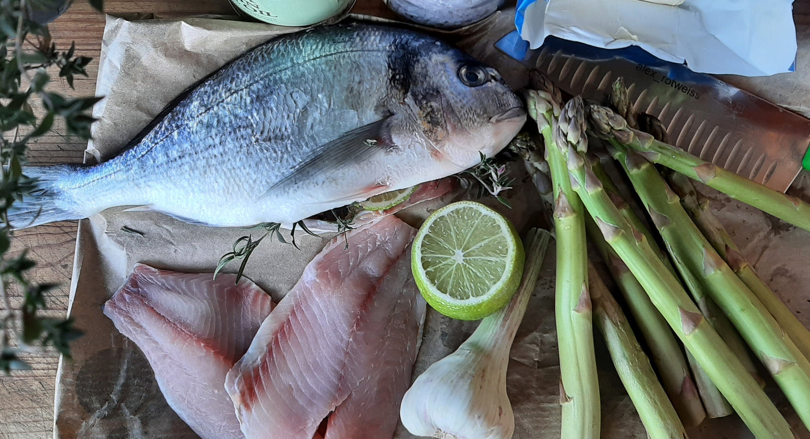 Eine Dorade, Fischfilet, Limette, Knoblauch und grüner Spargel.