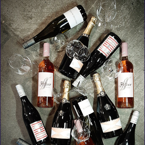 Jede Menge Sekt- und Weinflaschen auf dem Betonboden sowie Weingläser.